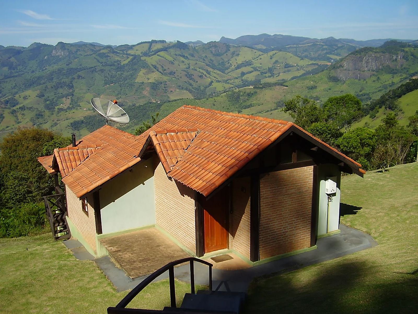 Chalé de tijolos com telhado de barro diante do vale da Serra da Mantiqueira
